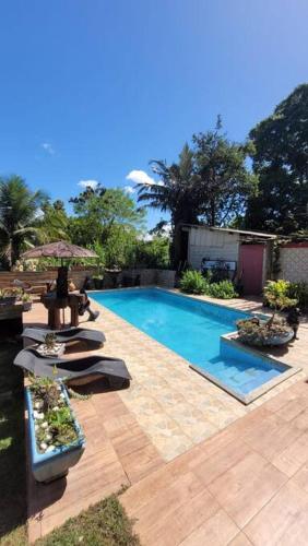 a swimming pool with lounge chairs and an umbrella at Chácara super aconhegante in Vila Velha