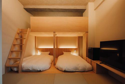 a bedroom with two bunk beds and a television at 無垢　入船の宿 in Kure