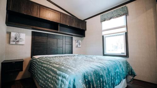 een slaapkamer met een bed met een blauw dekbed en een raam bij 3 Bedroom Cottage St. Andrews Lane 20 in Keene