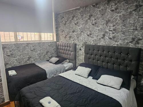 um quarto com 2 camas e uma parede de pedra em Colisseum Roma - El cubo movistar campin em Bogotá