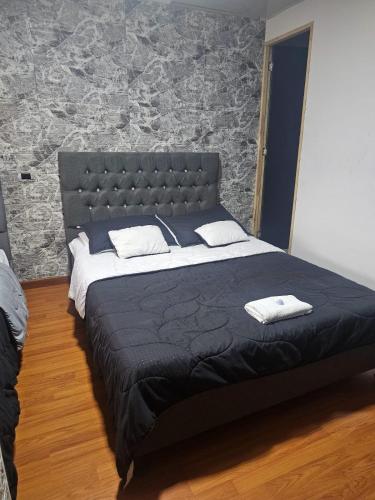 a large bed in a bedroom with a stone wall at Colisseum Roma - El cubo movistar campin in Bogotá
