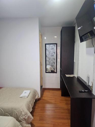 um quarto com uma cama, uma secretária e uma janela em Colisseum Roma - El cubo movistar campin em Bogotá