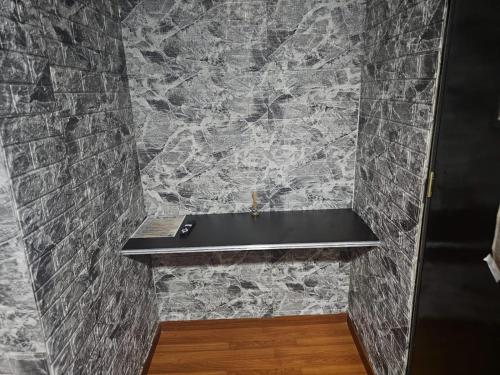 a bathroom with a stone wall with a black bench at Colisseum Roma - El cubo movistar campin in Bogotá