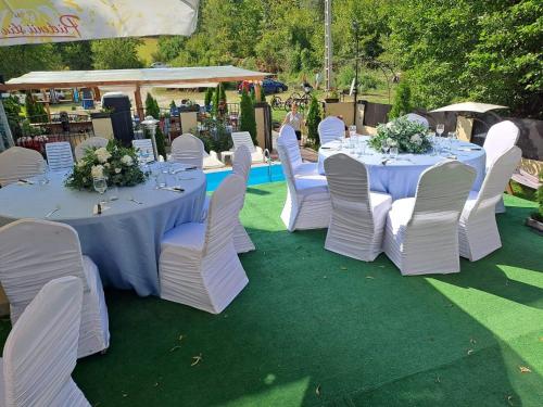 un groupe de tables avec des chaises blanches et des fleurs dans l'établissement Casa de vacanță MARA emd, à Eşelniţa