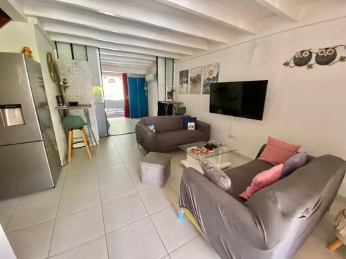 a living room with a couch and a flat screen tv at Villa cosy, piscine et plage. in Les Trois-Îlets