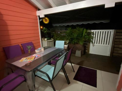 a dining room with a table and purple chairs at Villa cosy, piscine et plage. in Les Trois-Îlets