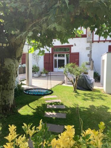 un jardin avec une balançoire en face d'une maison dans l'établissement Location Eyheraldia votre Triplex au cœur du Pays Basque, à Hasparren