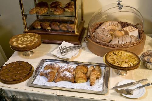 Una mesa con varios tipos de pasteles y cestas de pan. en Hotel De La Ville, en Saint Vincent