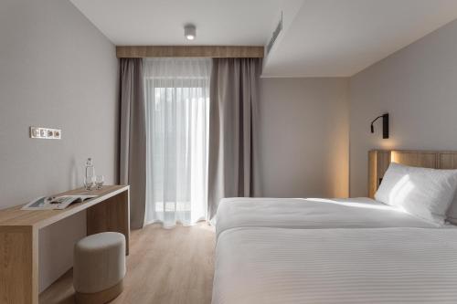 a hotel room with a bed and a desk and a window at Termy Karkonosze Resort & Spa koło Karpacza in Staniszów