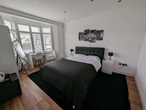 a bedroom with a large bed and two windows at Luxury Hotel Rooms in Palmers Green