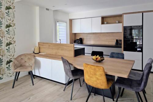 uma cozinha com uma mesa de madeira e cadeiras em L'HARMONIE, Appartement 2 chambres proche du lac, calme et lumineux em Annecy