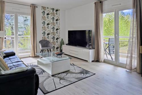 uma sala de estar com um sofá e uma televisão em L'HARMONIE, Appartement 2 chambres proche du lac, calme et lumineux em Annecy