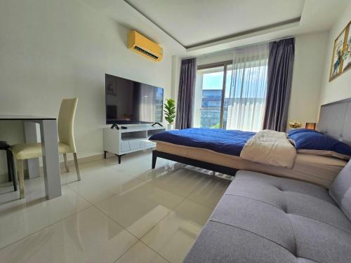 een slaapkamer met een bed en een tv en een bank bij Laguna beach condo resort 3 maldives pattaya top pool view ลากูน่า บีช คอนโด รีสอร์ต 3 พัทยา in Jomtien Beach