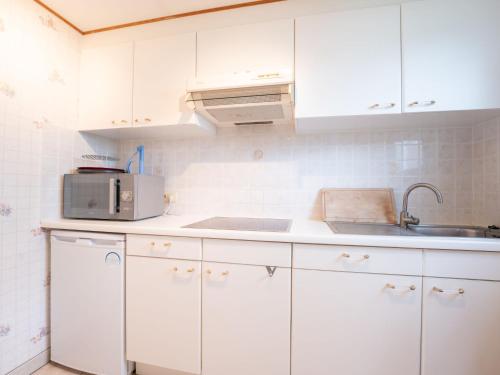 cocina con armarios blancos, fregadero y microondas en Holiday Home Edelweiss by Interhome, en De Haan