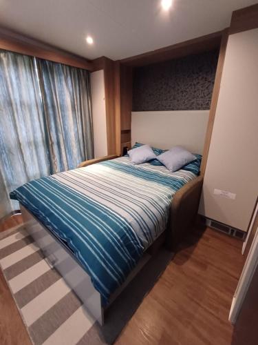 a bedroom with a bed with blue sheets and a window at Luxury Pods at Mornest Caravan Park, Anglesey in Gaerwen