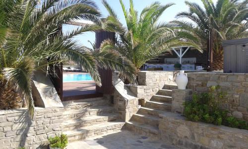 a stone wall with palm trees and a swimming pool at Maryo Village in Naousa