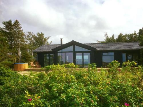 a black house with large windows in a garden at Holiday Home Elisenda - all inclusive - 625m from the sea by Interhome in Skagen