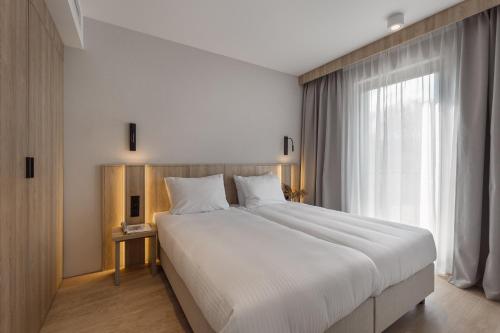 1 cama blanca grande en una habitación con ventana en Termy Karkonosze Resort & Spa en Staniszów