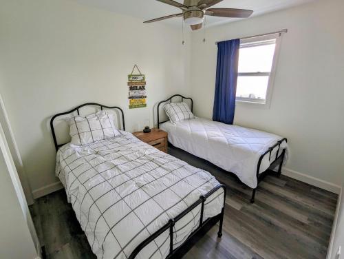 1 Schlafzimmer mit 2 Betten und einem Deckenventilator in der Unterkunft Newly Renovated 2 Bedroom Beach Front Condo 3A in Lanark