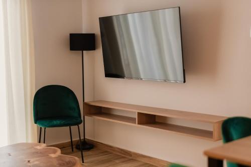 a television hanging on a wall with a green chair at Ethra Suite 2 in Volos