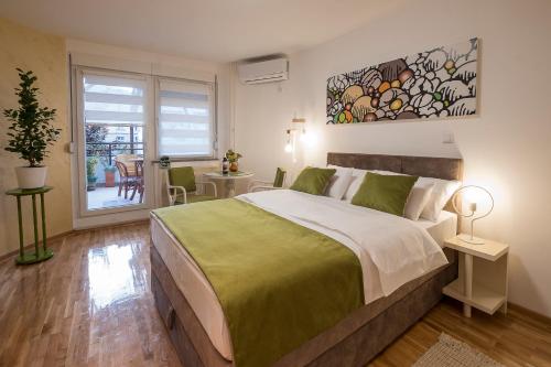 a bedroom with a large bed and a table with chairs at Cozy studio with a terrace near Slavija square in Sajmište