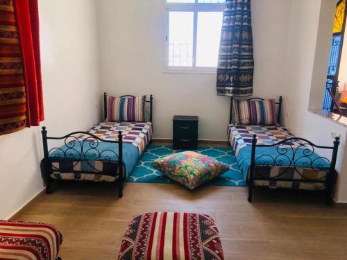 a room with two twin beds and a window at Essaouira à louer, appartement avec piscine privée in Bou Mkila