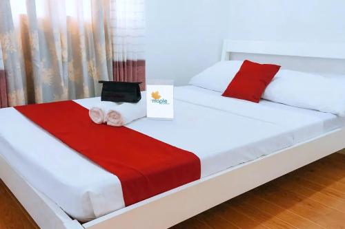 a bed with a red and white blanket on it at MMaple Residences Talisay in Talisay