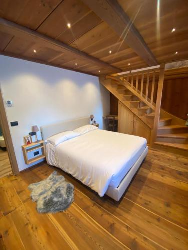 - une chambre avec un grand lit et un escalier dans l'établissement DRESALWOALD APPARTAMENTI, à Gressoney-Saint-Jean