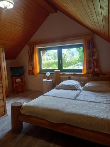 a bedroom with a large bed and a window at Na Brzegu in Szczyrk