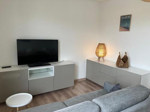un salon avec un canapé et une télévision à écran plat dans l'établissement La Teste cœur de ville, à La Teste-de-Buch