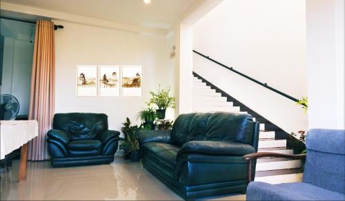 a living room with two leather chairs and stairs at Ananthaya -the infinity in Wadduwa