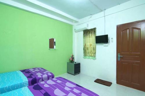a bedroom with a purple bed and a door at BOTANIA HOMESTAY BATAM in Nongsa