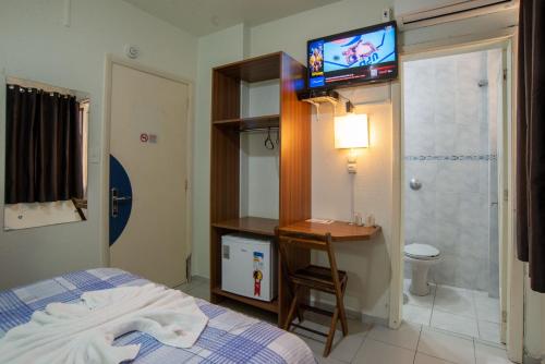 1 dormitorio con 1 cama, escritorio y TV en Bandeira Hotel, en Caxias do Sul