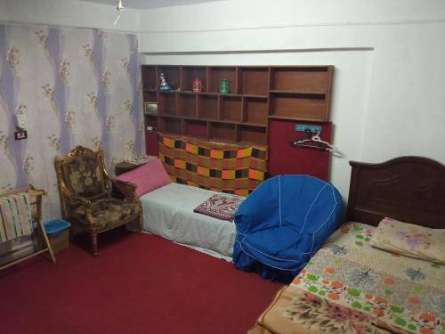 een kleine slaapkamer met een bed en een stoel bij Flower Roomsللرجال فقط in Alexandrië