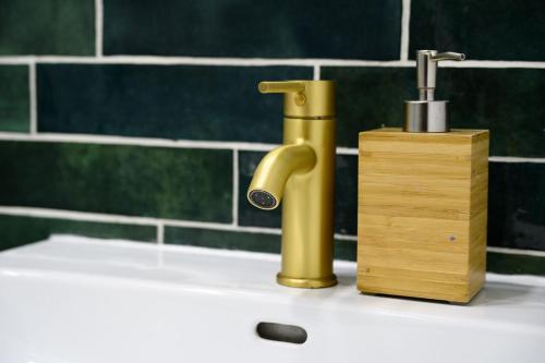 a bathroom sink with a gold faucet and a wooden block at Belgrade CITY CENTER Apartments in Belgrade