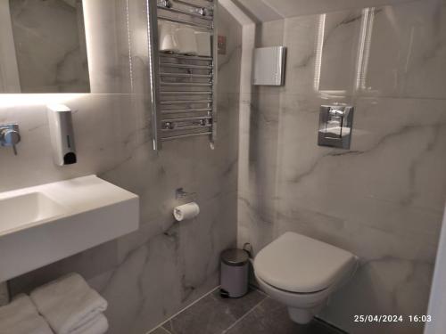 a white bathroom with a toilet and a sink at NOX Kensington in London