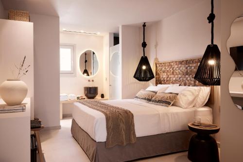 a bedroom with a large bed with black pendant lights at Enalion Suites Sifnos in Platis Yialos Sifnos