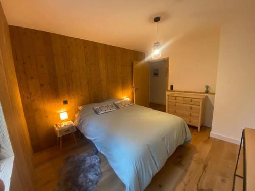 a bedroom with a bed and a wooden wall at Appartement T2 de Standing Neuf 6-8 personnes avec Balcon et Jardinet au Pied des Pistes à Combloux in Combloux