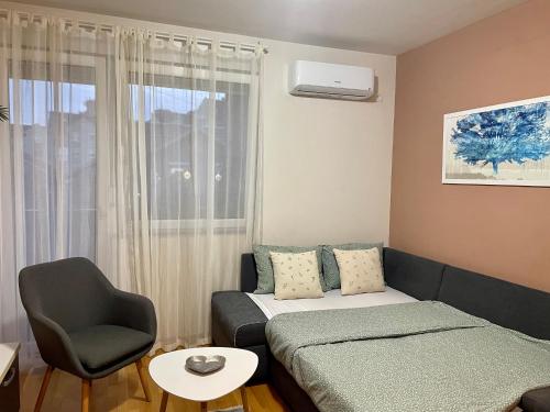 - un petit salon avec un lit et une chaise dans l'établissement Apartman Oaza, à Novi Sad