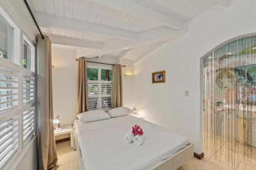 a white bedroom with a bed and a window at Villa Papaya in Willemstad