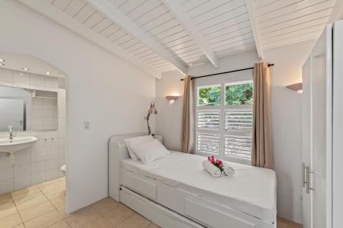 een witte slaapkamer met een bed en een raam bij Villa Papaya in Willemstad
