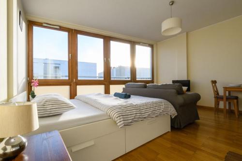 a large bed in a room with large windows at Luxury apartment Piękna in Warsaw