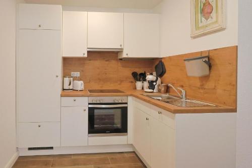 eine Küche mit weißen Schränken und einer Spüle in der Unterkunft Jagdhaus zu Amtern Apartment Rose in Holdorf