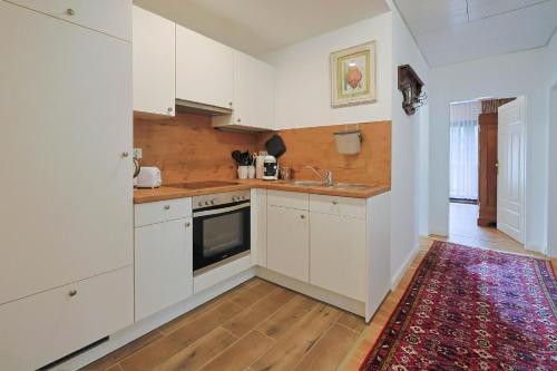 eine Küche mit weißen Schränken und einem Teppich in der Unterkunft Jagdhaus zu Amtern Apartment Rose in Holdorf