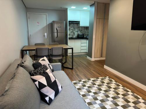 a living room with a couch and a kitchen with a table at Flat- mercure c/ quarto, sala e coz - Moema in São Paulo