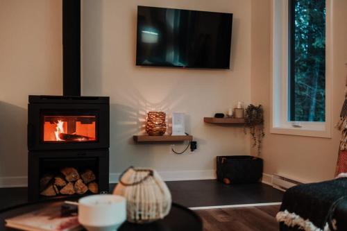 a living room with a fireplace and a tv on the wall at Nature & lake access Tremblant in Saint-Rémi-dʼAmherst