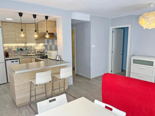 une cuisine avec un comptoir et une chaise rouge dans l'établissement Estación Tren Reformado 2 habitaciones, à Alicante