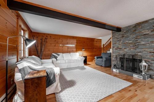 sala de estar con sofá blanco y chimenea en Chalet Mont Cascades w/ Spa & Fibre Optic Internet en Cantley