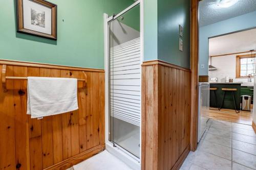 a bathroom with a walk in shower next to a wooden wall at Chalet Mont Cascades w/ Spa & Fibre Optic Internet in Cantley