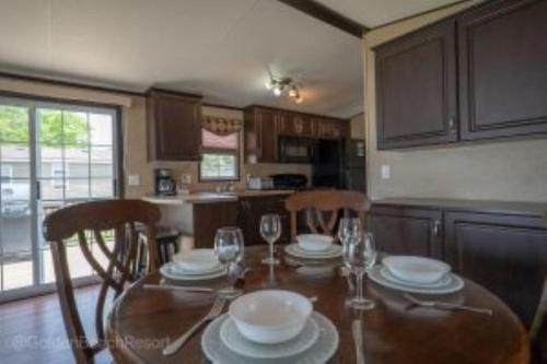 una cocina con mesa y sillas con vasos y platos en 2 Bedroom Harbor Front Cottage 2, en Roseneath